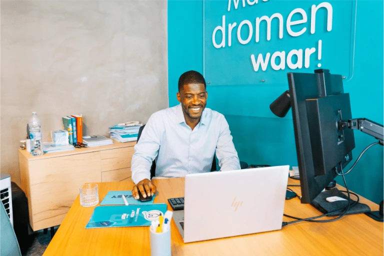 Hypotheekexpert van hypotheek.winkel werkt aan zijn bureau op een laptop in een kantoor.